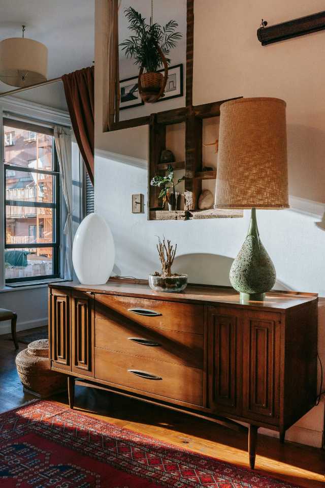 thai inspired living room with hand crafted wood cabinet, green lamp, and red area rug